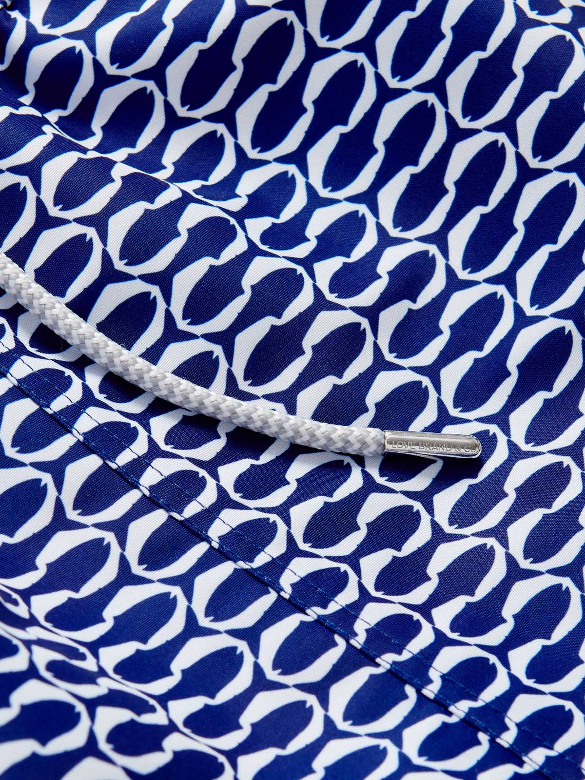 Close-up detail of Men's Pine Cay Fish Staniel Swim Shorts featuring a blue and white geometric fish pattern with a white drawstring.